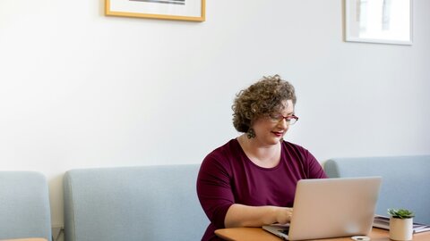Middle aged working woman sitting with laptop at table