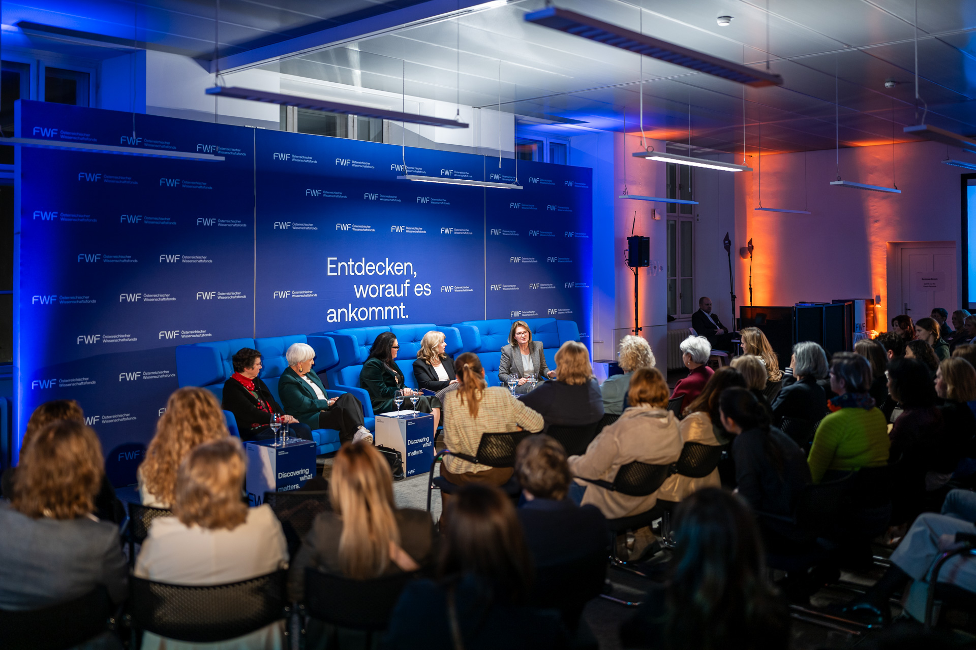 Blick auf die Diskutantinnen von hinten links über die Köpfe des Publikums
