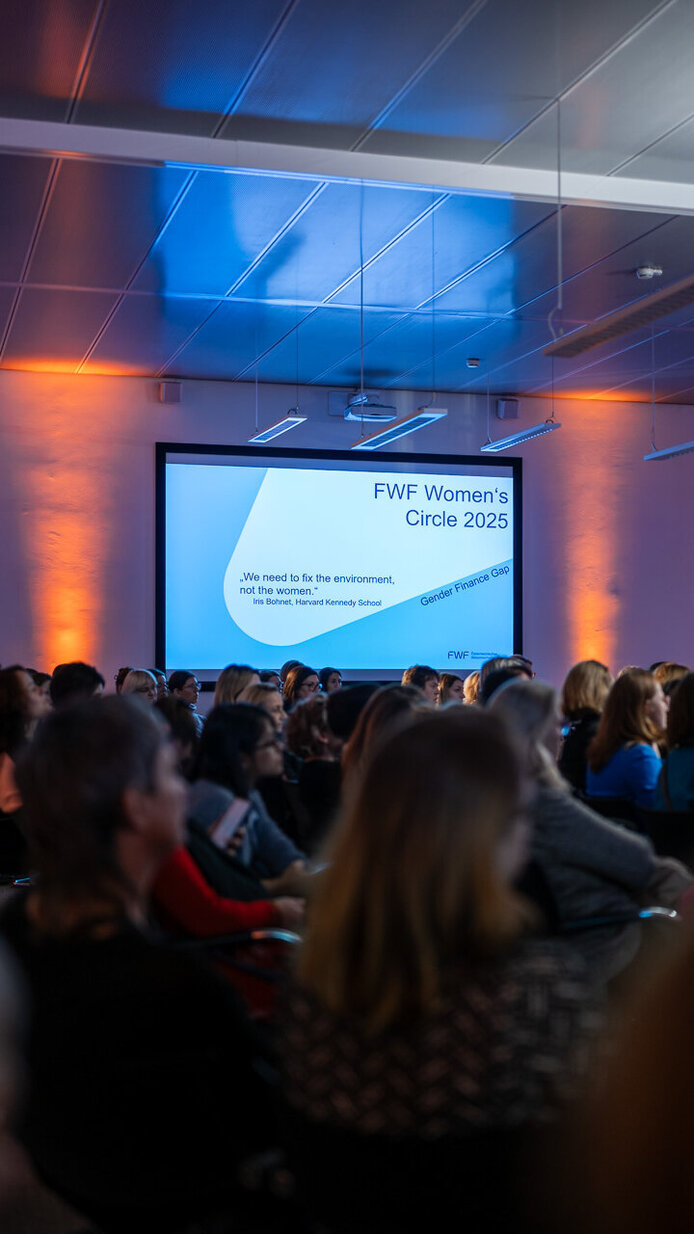 Blick über die Köpfe des Publikums auf eine Video Wall