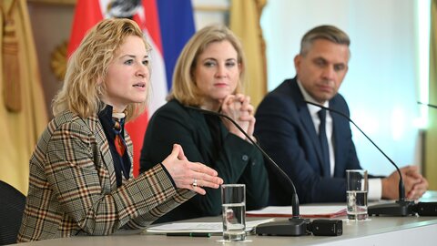 Wissenschaftsministerin Eva-Maria Holzleitner, Außenministerin Beate Meinl-Reisinger und Wirtschaftsminister Wolfgang Hattmannsdorfer mit Mikrofon bei der Pressekonferenz