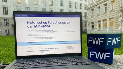 Laptop mit Ansicht der Website des Historischen Forschungsradars vor der ehem. Postsparkasse am Georg-Coch-Platz