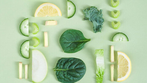 Diverse Obst- und Gemüsescheiben und Blätter vor grünem Hintergrund