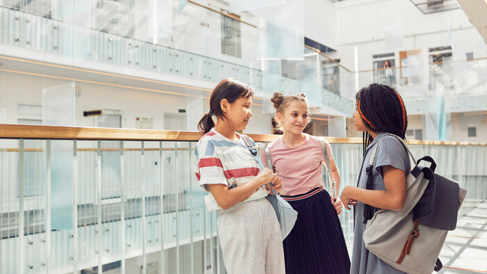 Drei Schülerinnen unterhalten sich im Schulgebäude während einer Pause