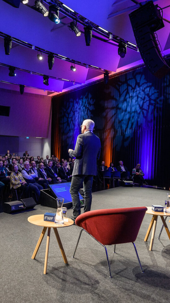 Ansicht von seitlich hinter der Bühne auf Axel A. Brakhage (DFG) und aufs Publikum