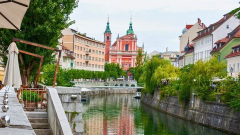 A promenade along a river lined with greenery in a historic old town