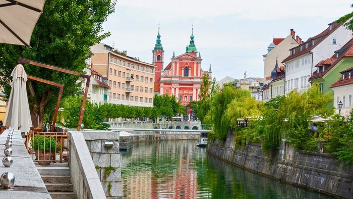 Promenade entlang eines begr&uuml;nten Flussverlaufs in einer historischen Altstadt