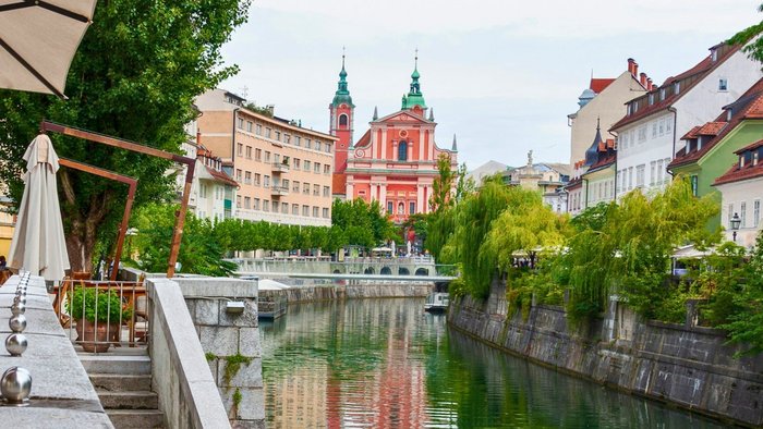 Promenade entlang eines begr&uuml;nten Flussverlaufs in einer historischen Altstadt
