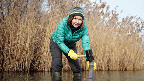 [Translate to English:] Christa Schleper entnimmt eine Sedimentprobe aus der Donau