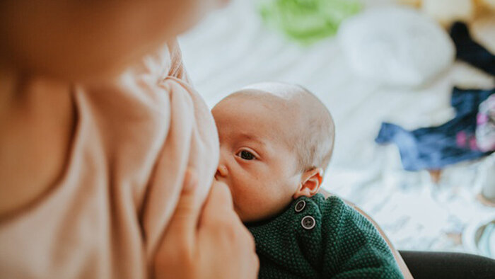 Stillende Mutter mit Baby am Arm 