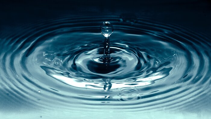 Ein Wassertropfen trifft auf eine Wasseroberfläche auf