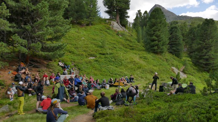Teilnehmer:innen der Regional Mountain Conference 2026 stehend und sitzend auf einer Lichtung neben dem Wanderweg