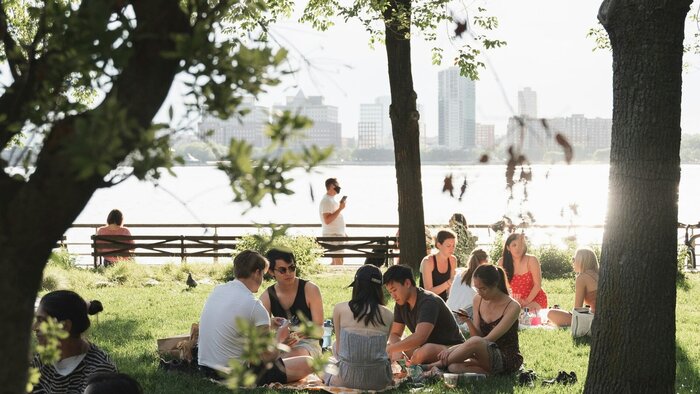 Menschen im Park bei Sonnenschein mit Hochhäusern im Hintergrund