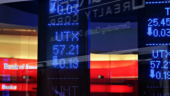 Screen mit Börsekursen vor einer Bank 