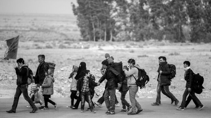 Ein Gruppe Erwachsene und Kinder auf der Flucht.