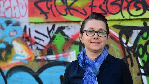 Oksana Havryliv in front of a wall with graffiti