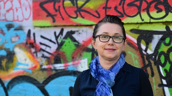 Oksana Havryliv vor einer Wand mit Graffitis 