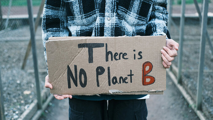 Jemand hält ein Pappschild mit der Aufschrift "There is NO Planet B"