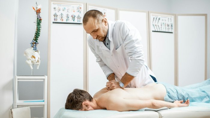 Physiotherapeut behandelt einen Patienten mit R&uuml;ckenschmerzen