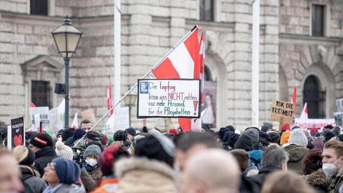 Demonstrierende, mit &Ouml;sterreichfahne und Schildern gegen die Corona-Impfung