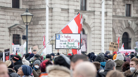 Demonstrierende, mit Österreichfahne und Schildern gegen die Corona-Impfung
