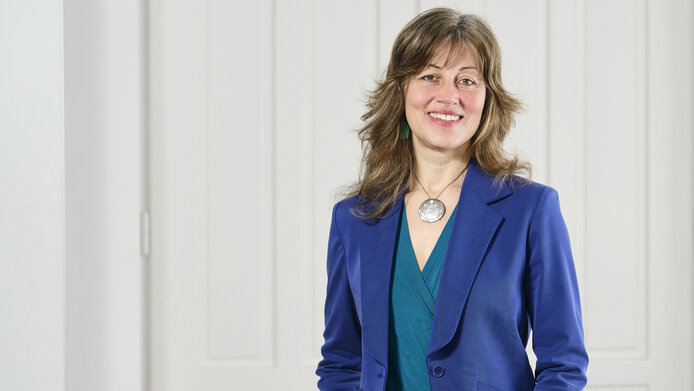 Porträt Weiss-Preisträgerin Manuela Schmidt in blauem Hosenanzug vor weißer Flügeltüre