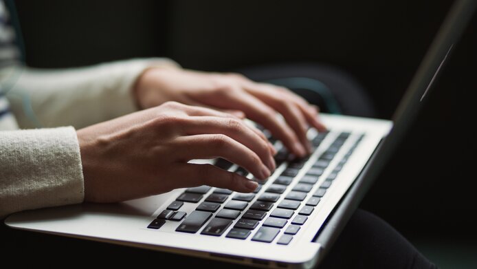 Laptop-Tastatur mit eingebender Hand.