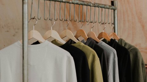 Sweatshirts on hangers are hanging from a metal rod in a store