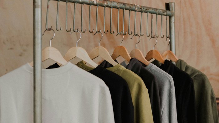 Sweatshirts auf Kleiderb&uuml;geln h&auml;ngen an einer Metallstange in einem Shop