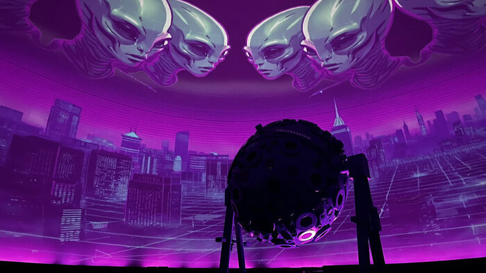 Pink-lila-blaues Foto einer Projektion mit EXO:Aliens im Planetarium Wien