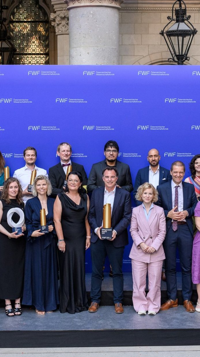 Der FWF-Wittgenstein-Preisträger Markus Aspelmeyer im Kreise aller ausgezeichneten Forschenden der Austrian Science Awards 2026 im Rathaus vor der FWF-Logowand