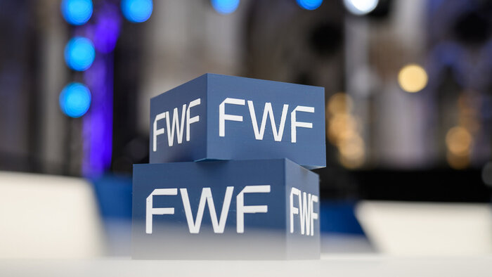 Zwei &uuml;bereinander gestapelte blaue Quader mit wei&szlig;em &bdquo;FWF&ldquo;-Logoschriftzug